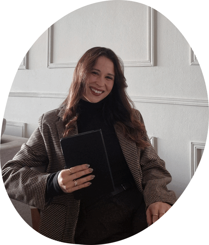 Sarah segurando um caderno, olhando para a câmera
